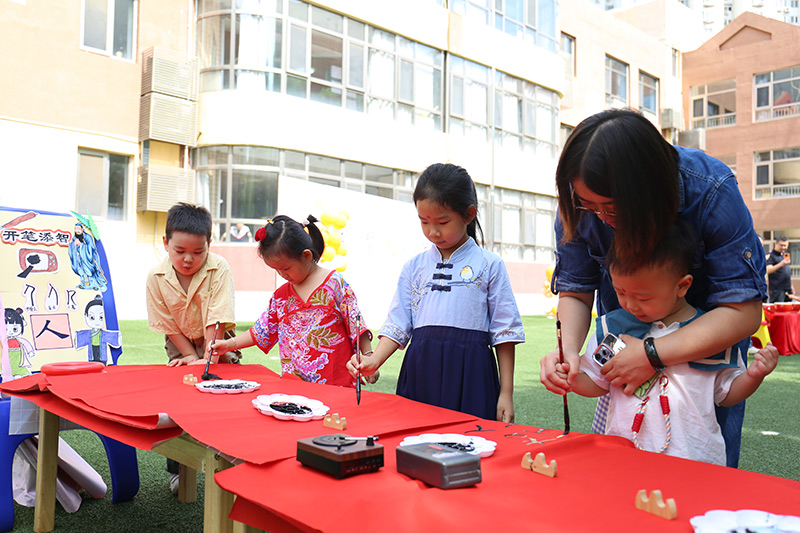 9月1日,北京市朝陽區望京新城幼兒園以“開筆啟智,禮潤星寶”為主題的秋季開學典禮拉開帷幕。幼兒園開展了朱砂啟智、擊鼓鳴智、開筆啟智、盥洗禮等傳統文化互動游戲,願知禮明禮、潛心向學的種子在孩子們的心中生根發芽。圖為老師帶小朋友開筆啟智。北京市朝陽區教委供圖