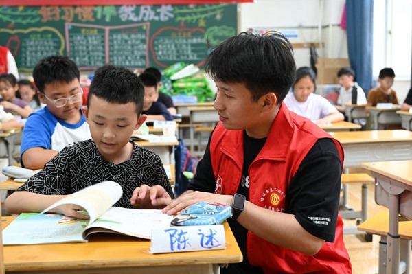 鄭州市二七區暑托班的志願者輔導孩子寫作業。人民網記者王玉興攝
