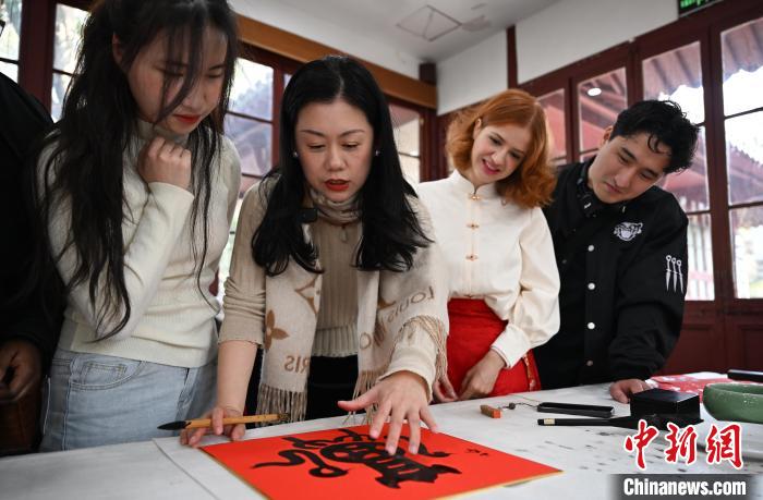 1月20日,西泠印社社員李硯(左二)為外籍留學生講述蛇年福字貼創作靈感。當日,來自巴西、馬來西亞、加納、哈薩克斯坦的外籍留學生在浙江杭州西泠印社體驗福貼、春聯和篆刻,感受古老的中國傳統文化。中新社記者 王剛 攝
