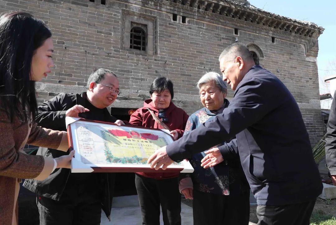 河南省許昌市建安區袁庄，曹明（左二）將修復好的革命烈士証明書交到袁鬆鶴烈士的家屬手中。