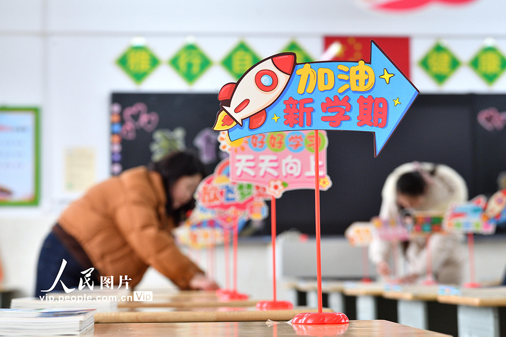 2026年3月2日,在湖北襄陽保康縣實驗小學,教師正在整理學生課桌上的新教材,認真做好開學前的各項准備工作。楊韜攝(人民圖片網)