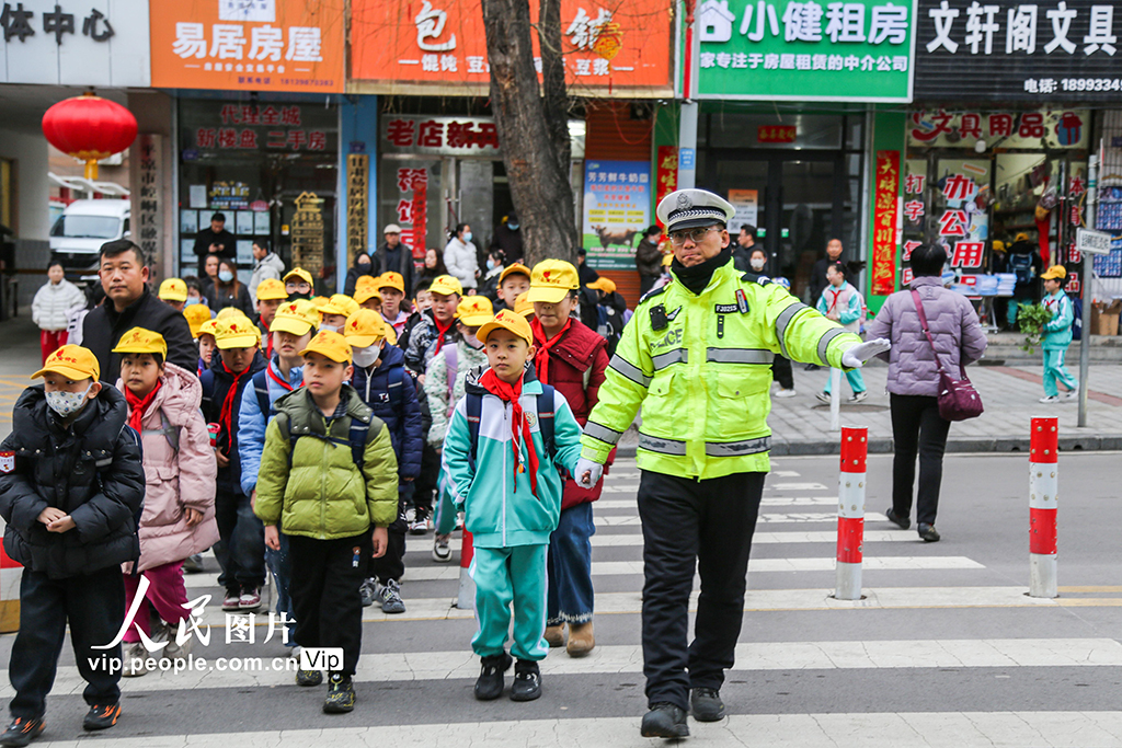 2026年3月2日,甘肅平涼市公安局崆峒分局交管大隊執勤交警在學校門前的斑馬線上,引導學生安全通過馬路。鄭兵攝(人民圖片網)