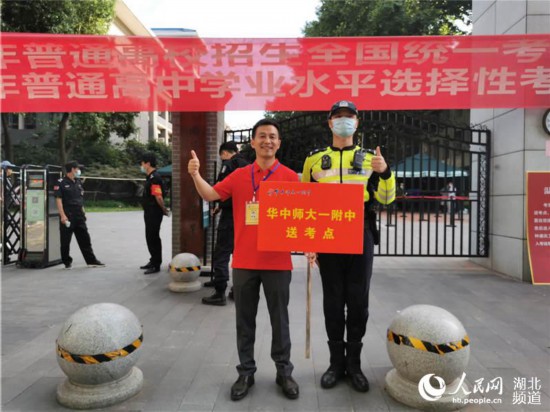 湖北省武昌实验中学考点门前,华师大一附中送考老师与武昌交警共同合影,希望考生一切顺利。人民网 肖璐欣摄