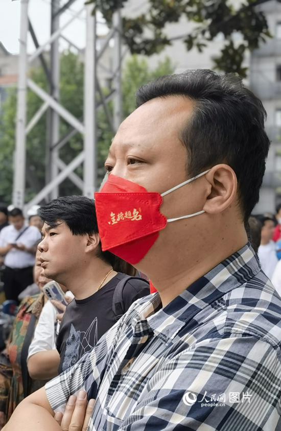 6月7日早，在武漢市第二十六中學考點外，送考家長戴著印有“金榜題名”的口罩。人民網 周雯攝