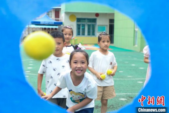 在肥西縣山南鎮中心幼兒園,孩子們在玩布洞投球游戲。 陳家樂 攝
