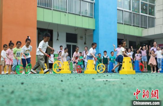 在肥西縣山南鎮中心幼兒園,孩子們在玩滾鐵環游戲。 陳家樂 攝