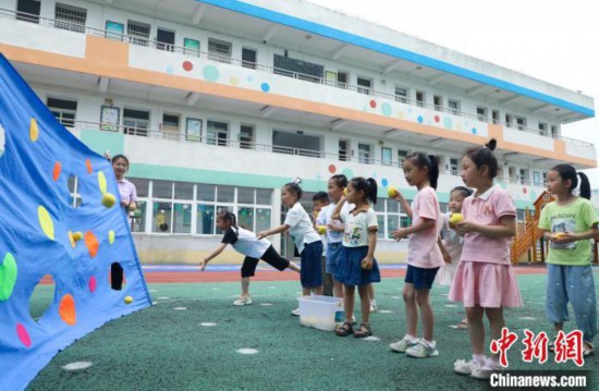 在肥西縣山南鎮中心幼兒園,孩子們在玩布洞投球游戲。 陳家樂 攝