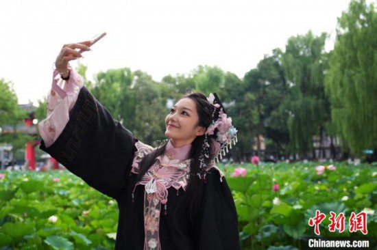 6月19日,时值一年毕业季,四川大学望江校区荷花池里的荷花盛开,成为了毕业生们的打卡圣地,吸引了众多毕业生拍照留念。图为毕业生在荷花池边拍照留念。中新社记者 安源 摄
