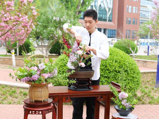 中國傳統插花非遺傳承人、園林學院侯芳梅老師的學生胡鈺陽正在演示盤花制作
